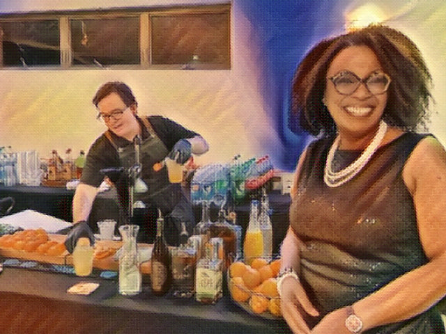 A smiling guest at an Executive Beverage bar while a bartender pours drinks behind her.