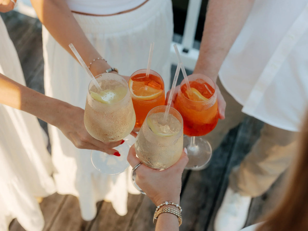 Four guests in white clinking spritz cocktails made by Executive Beverage.