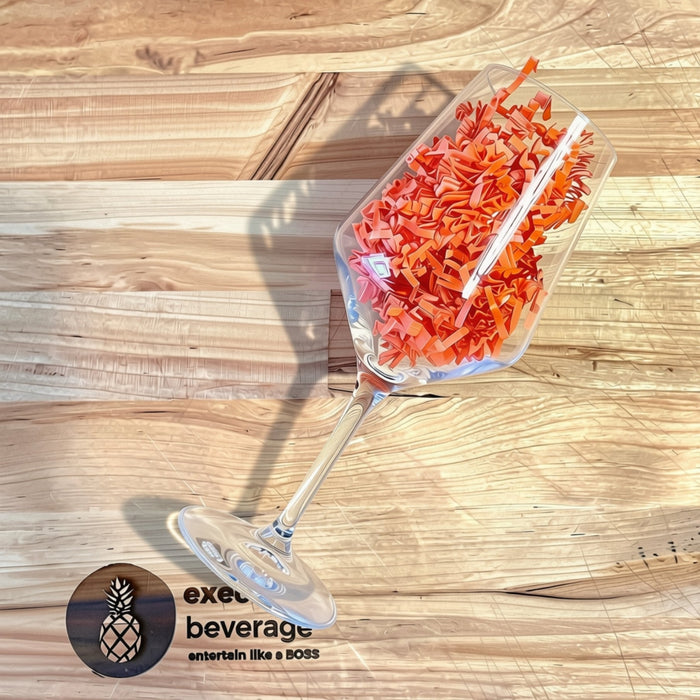 A wine glass tipped on its side spilling orange paper straws across a butcher's block, Executive Beverage mark below.