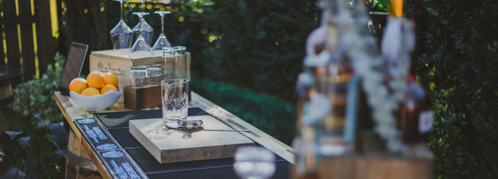 Spirits and glassware on an outdoor bar at dusk at an autumn event.