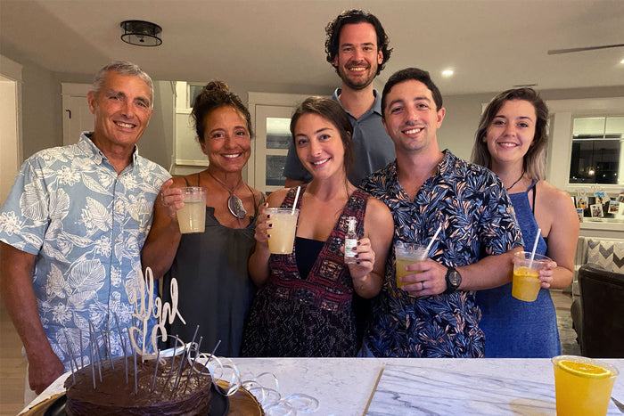 A family gathered around a home kitchen island with fresh cocktails poured by Executive Beverage, leaving the kitchen free for cooking.