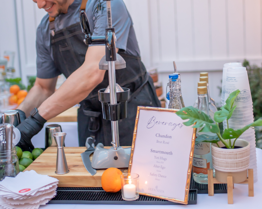 An Executive Beverage Crush Kit bar set up outdoors: rectangle bar mat, butcher's block and the manual citrus juicer, with Waterman's Perfect Crush and fresh oranges