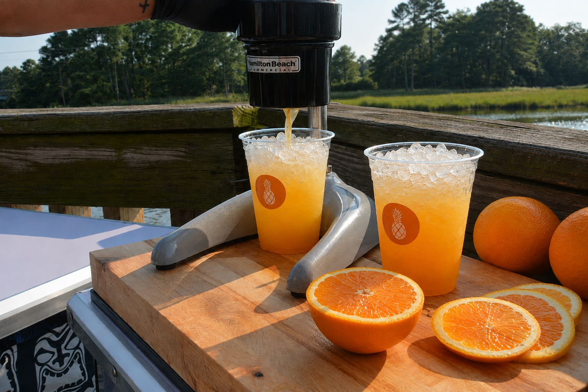 An Executive Beverage Crush Kit set up with the crusher, fresh oranges and two poured crushes on a butcher's block