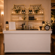 Load image into Gallery viewer, The Hampton bar styled with a gold shelf and white floral arrangements
