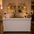 Load image into Gallery viewer, A pair of Gold Shelf étagères set behind the Hampton bar, dressed with wine bottles, stemware, candles and white florals.
