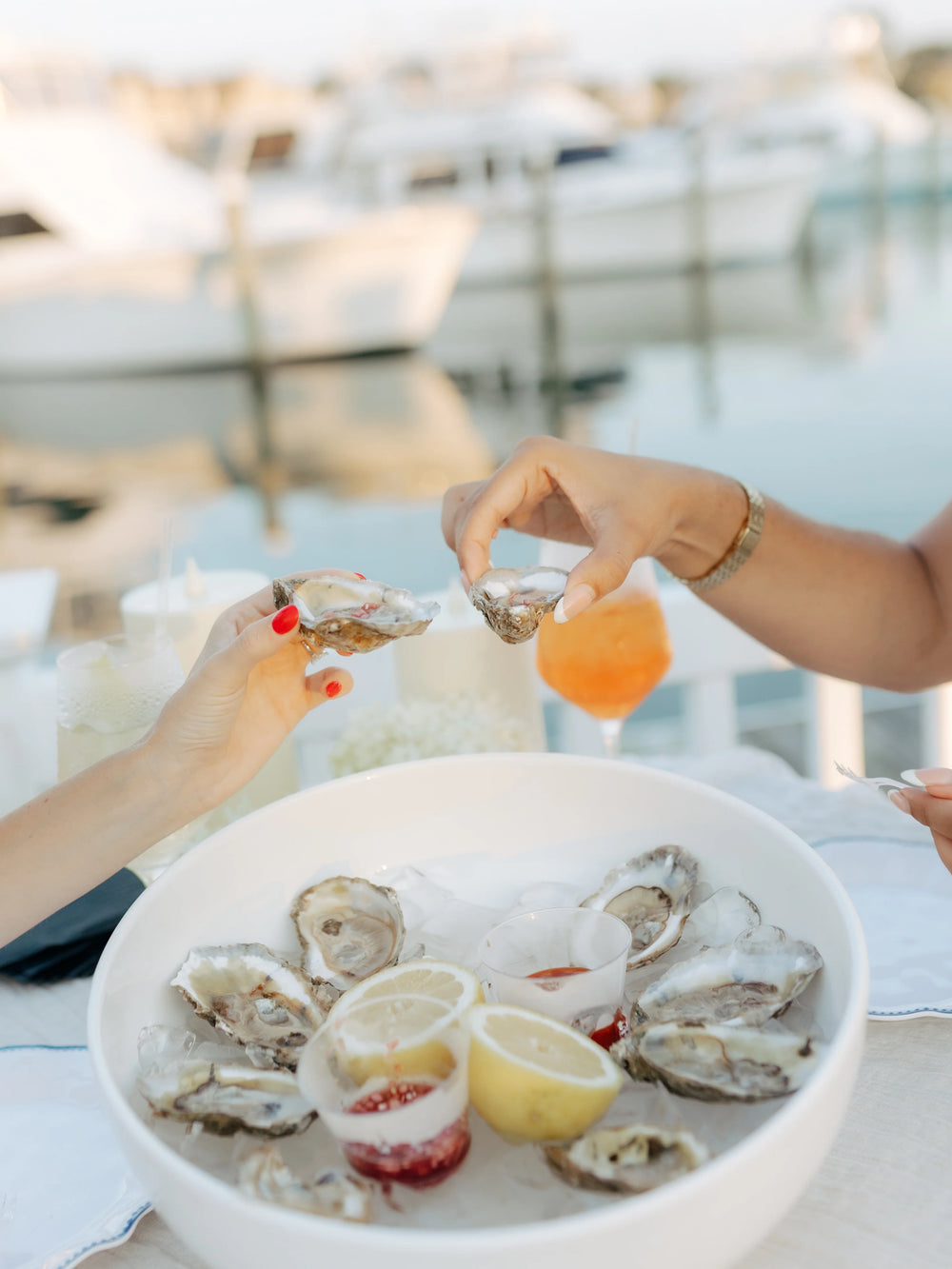 Guests sharing oysters and cocktails by the water at an Executive Beverage event in Hampton Roads.