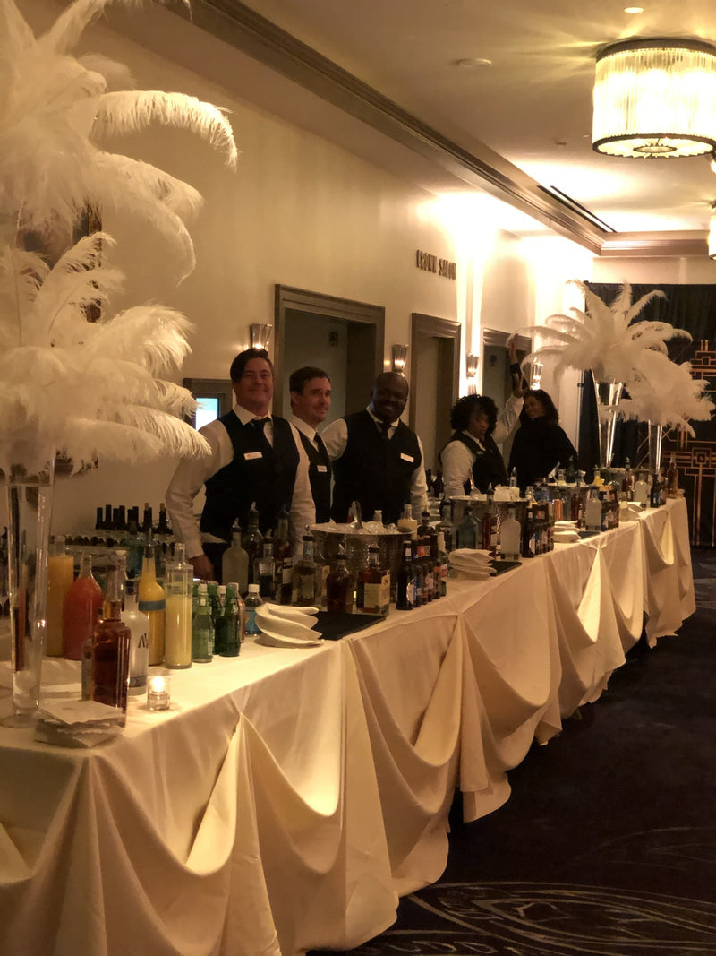 A banquet-length bar running the side of the Cavalier Hotel ballroom on New Year’s Eve, dressed with feather centerpieces and staffed end to end.