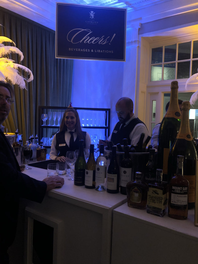A champagne and wine station under a Cheers! sign at the Cavalier Hotel on New Year’s Eve, lit in blue.