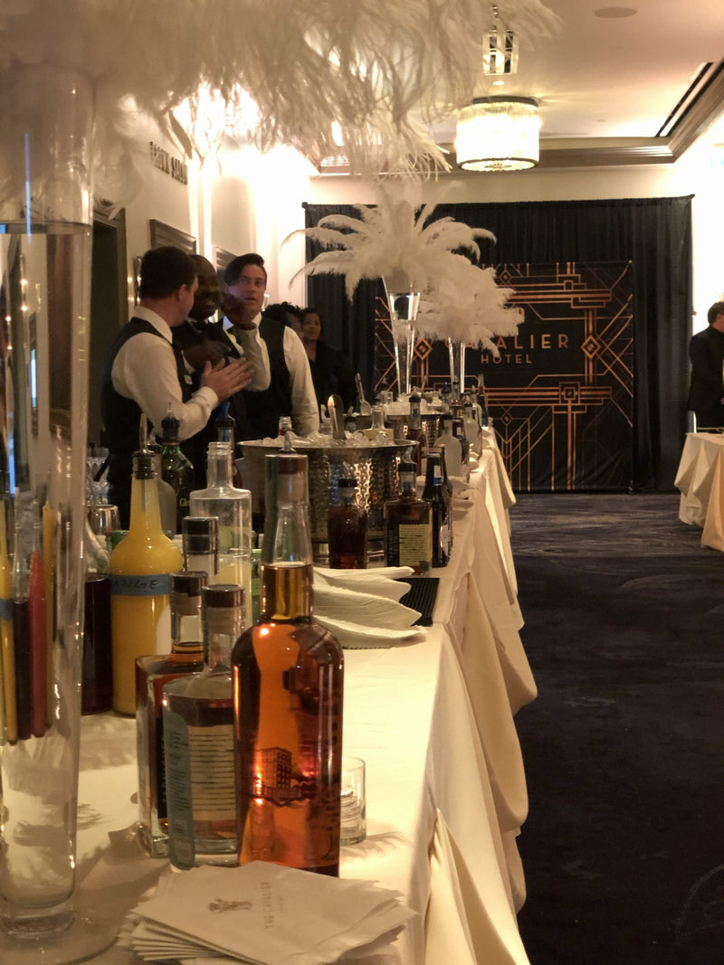 New Year’s Eve bar service at the Cavalier Hotel, a long spirits rail set against the ballroom’s Art Deco screen.