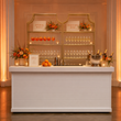 Load image into Gallery viewer, Two Gold Shelf étagères behind a white event bar as an Aperol Spritz and sparkling wine station, with printed signage and autumn florals.
