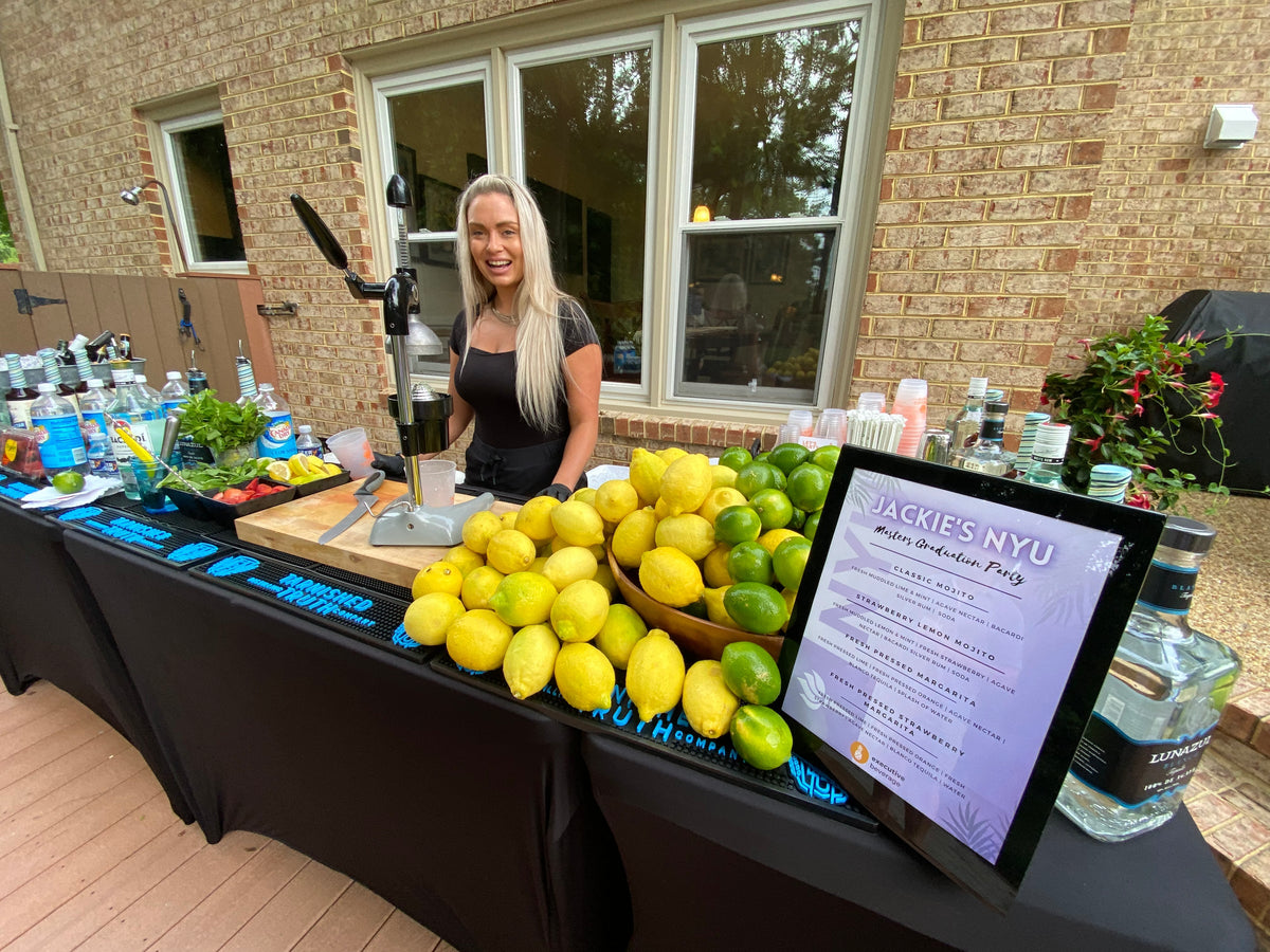 An Executive Beverage bartender working a full backyard bar stacked with fresh citrus at a Chesapeake house party.