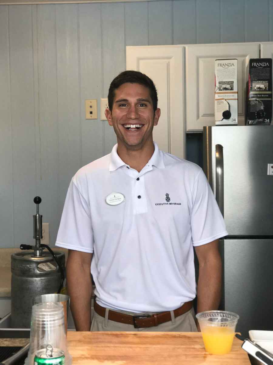 Dennis M. Ferrigno, Jr., founder of Executive Beverage, behind the bar at a private event with a draft tap and glassware set up beside him.