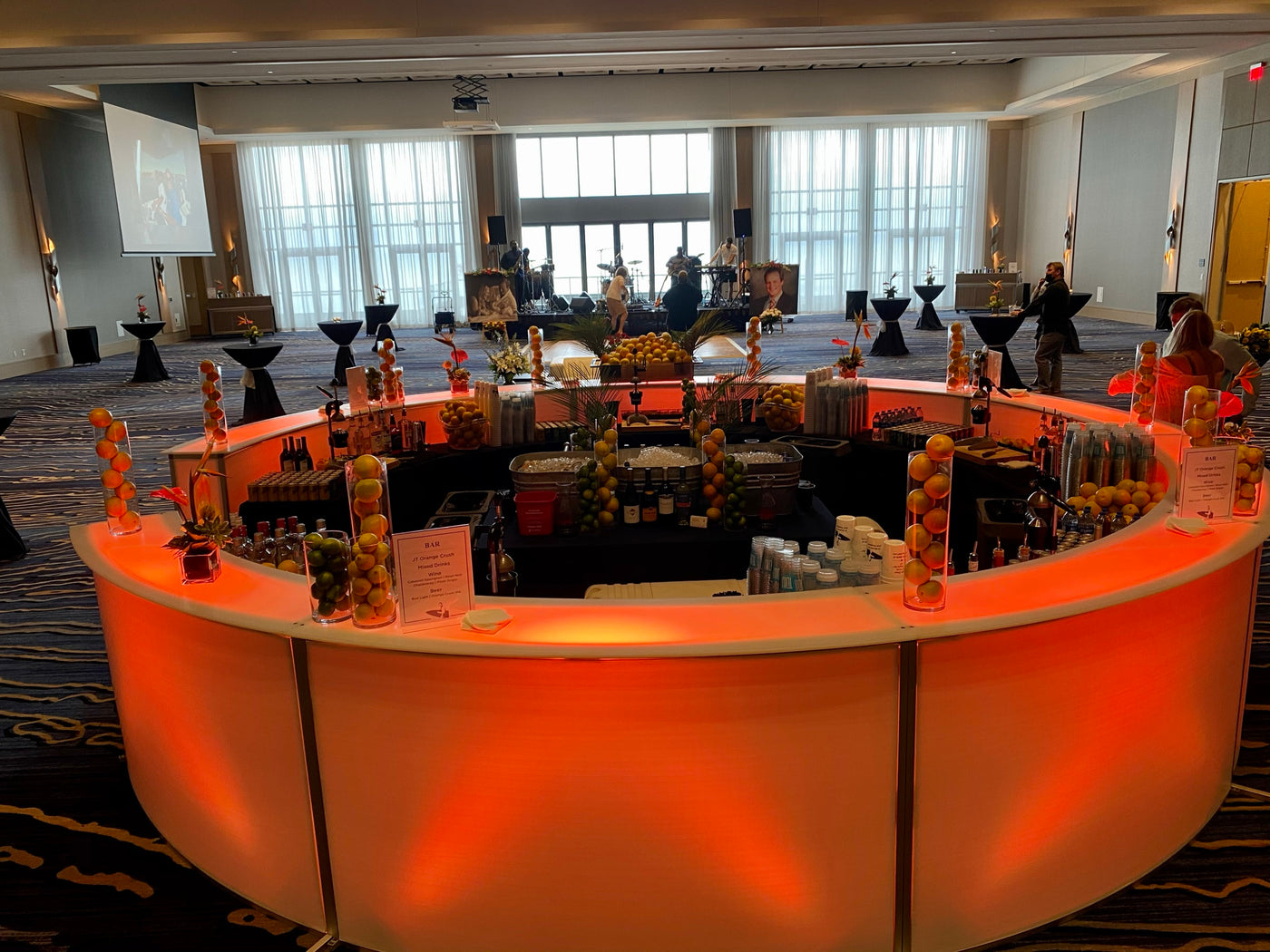 A full oval LED bar island built in the centre of a hotel ballroom, lit from within and stocked the whole way round for a conference reception.