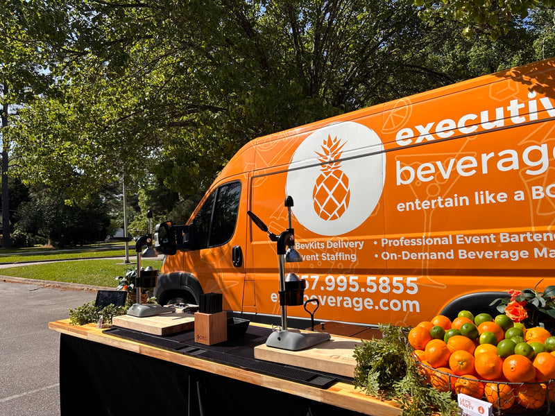The Executive Beverage van parked behind a fresh-citrus bar at a Portsmouth Police community event, crates of oranges and a press ready to serve.